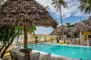 a resort with a swimming pool with straw umbrellas at ZAN Uhuru Beach in Jambiani