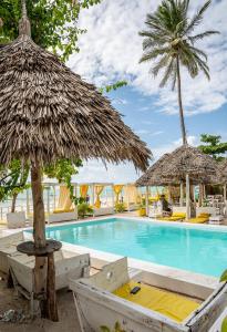 a swimming pool with two straw umbrellas and a resort at ZAN Uhuru Beach in Jambiani