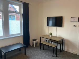 ein Raum mit einem Tisch und einem Fernseher an der Wand in der Unterkunft Duncan - 2Bdrm Sleeps 5 Good for Contractors in Gateshead