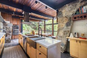 a kitchen with wooden cabinets and a stone wall at Two Creeks Treehouse in Mill Valley