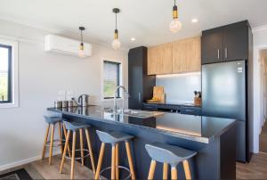 a kitchen with a blue counter and bar stools at Raglan Sun Seekers Retreat in Raglan +18 photos