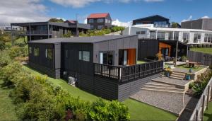 a black house on a hill with a garden at Raglan Sun Seekers Retreat in Raglan