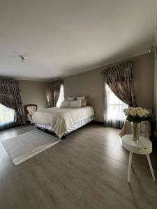 a bedroom with a bed and a table and windows at Paradiso Palazzo in Welkom +21 photos