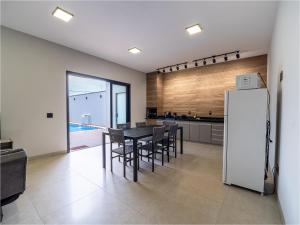 een keuken met een tafel, stoelen en een koelkast bij Casa com Piscina, Wi-Fi e Garagem in Pirassununga