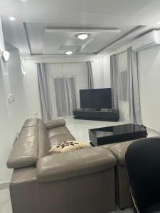 sala de estar con sofá de cuero y TV de pantalla plana en Happiness House Gambia, en Banjul