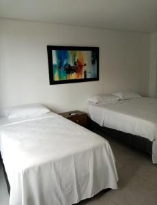 two beds in a hotel room with a picture on the wall at Paraíso en Bocagrande Apartaestudio in Estación El Salto