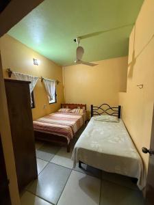 een slaapkamer met twee bedden en een plafondventilator bij La Casita De Marlen in Puerto Ángel