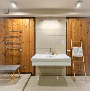 a bathroom with a white sink and wooden walls at Jauki Lauki in Lejasciems