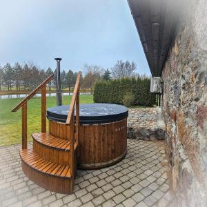 a hot tub sitting on a patio with two wooden stairs at Jauki Lauki in Lejasciems +39 photos