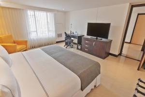 a bedroom with a bed and a desk and a television at Sonesta Hotel Cali in Cali