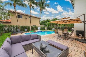 a patio with a couch and an umbrella next to a pool at Modern Miami Home with Patio and Pool in Country Walk