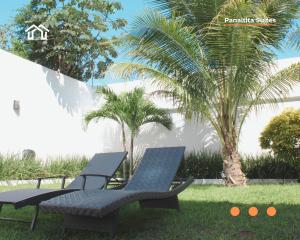 two chairs and a table in a yard with palm trees at PanaltitaSuites in Cancún