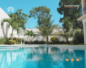 a swimming pool in front of a building with palm trees at PanaltitaSuites in Cancún