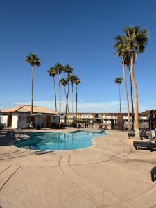 a swimming pool with palm trees in a resort at Travelodge by Wyndham Imperial - El Centro in El Centro