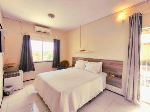 een slaapkamer met een wit bed en een raam bij Panorama Cumbuco in Cumbuco