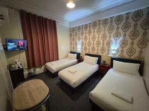 a hotel room with two beds and a table at Victorin House - All rooms are EN-SUITE in Portsmouth