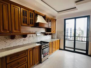 a kitchen with wooden cabinets and a stove top oven at Abat property Rental in Addis Ababa