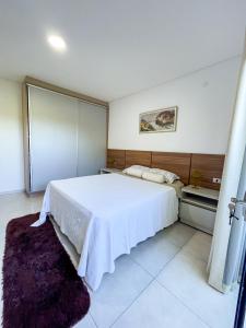 a bedroom with a large white bed and a purple rug at A estrenar departamento en la mejor playa in Encarnación