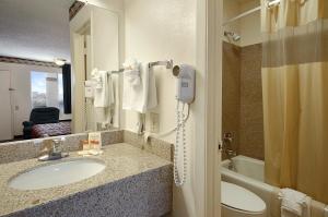 a bathroom with a sink and a toilet and a phone at Days Inn by Wyndham Dallas Irving in Irving