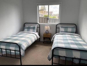 due letti in una stanza con finestra di Family Holiday Home Ulladulla a Ulladulla