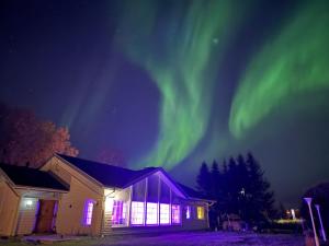 een gebouw met het noorderlicht in de nacht bij Arctic Luxe Retreat in Rovaniemi