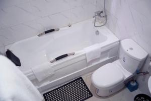 RayfieldNafik Suites的浴室配有卫生间和白色浴缸。