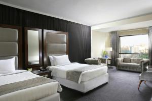 a hotel room with two beds and a couch at Four Points by Sheraton Lahore in Lahore +47 photos