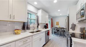Una cocina con gabinetes blancos y un fregadero y una mesa. en Updated Family Unit with Two King Beds, en Denver