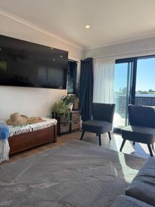 a bedroom with a large flat screen tv on the wall at Raglan Sun Seekers Retreat in Raglan