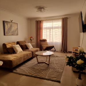 een woonkamer met een bank en een tafel bij Nadreya Nakuru Milimani Suite in Nakuru