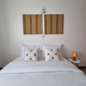 een slaapkamer met een wit bed met witte kussens bij Nadreya Nakuru Milimani Suite in Nakuru