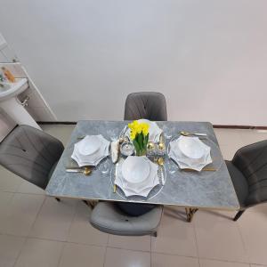 een tafel met borden en een vaas met bloemen erop bij Nadreya Nakuru Milimani Suite in Nakuru