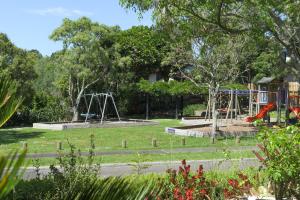a park with two swings and a playground at Parnwell Villa Apartment - The Tropical Oasis in Tauranga
