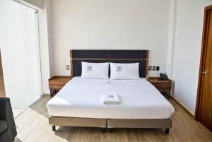 a bedroom with a large white bed with two pillows at Hotel Vía Norte - Business con parking y acceso rápido al Periférico in Tuxtla Gutiérrez