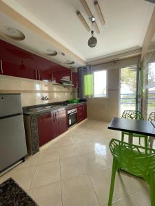 una cucina con armadi rossi e tavolo e sedie verdi di AfricaCup's hostel a Tamraght Ouzdar