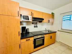 a kitchen with wooden cabinets and a sink and a microwave at NEU Apartmenthaus-Usedom Familie Stopp Kajüte 7 - Balkon - strandnah in Kölpinsee +22 photos