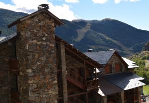 a stone building with a balcony and mountains in the background at La Devesa in Incles