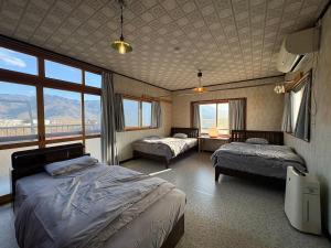 1 Schlafzimmer mit 2 Betten in einem Zimmer mit Fenstern in der Unterkunft 三ツ和のお宿 in Nakano