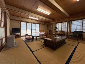 ein großes Wohnzimmer mit einem Tisch und einem TV in der Unterkunft 三ツ和のお宿 in Nakano