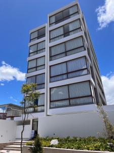 a tall white building with a tree in front of it at Nuevo y moderno departamento Quito Norte in Quito