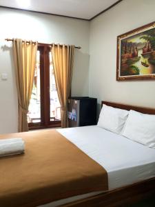 a bedroom with a bed and a painting on the wall at Vinandaka Homestay in Sanur