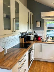 eine Küche mit weißen Schränken und einer Holzarbeitsplatte in der Unterkunft Modern Cabin With Panoramic Views In Aukland in Høyvik