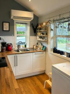 eine Küche mit weißen Schränken und einer Spüle und einem Fenster in der Unterkunft Modern Cabin With Panoramic Views In Aukland in Høyvik