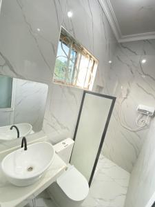 een witte badkamer met een wastafel en een spiegel bij HalmaHome Two Bedroom Apartment in Zanzibar City