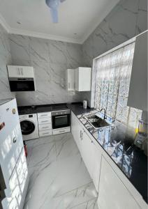 een witte keuken met een wastafel en een koelkast bij HalmaHome Two Bedroom Apartment in Zanzibar City