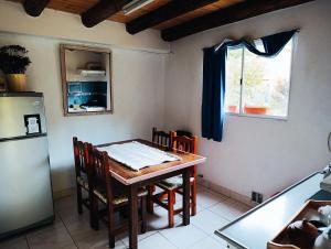 a kitchen with a table with chairs and a refrigerator at Nuestro Lugar in El Bolsón