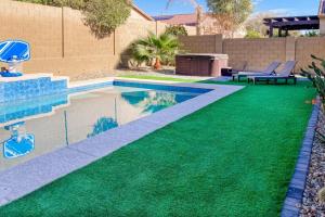 een achtertuin met een zwembad met groen gras bij Sweet Home Sherman in Goodyear