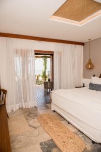 um quarto com uma grande cama branca e uma janela em Carlore Hotel Taíba em Taíba