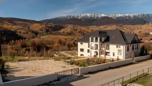 een groot wit huis aan een weg met bergen op de achtergrond bij Zodia Craiului in Peştera