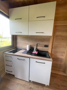 a kitchen with white cabinets and a sink at Koliba Relax Point in Potoci